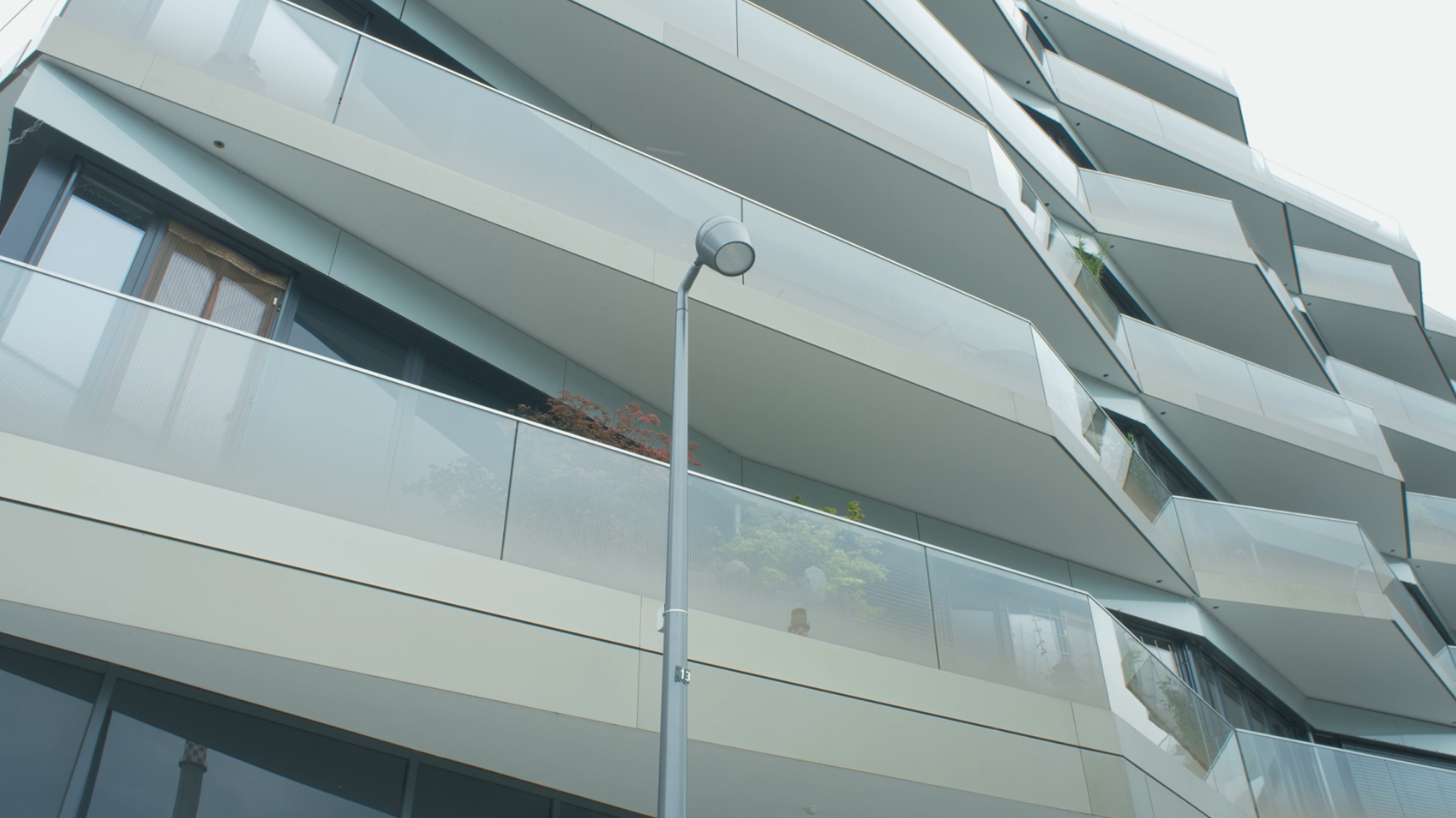 Das Foto zeigt eine moderne Häuserfassade, die fast nur aus Glas und Balkonen besteht.